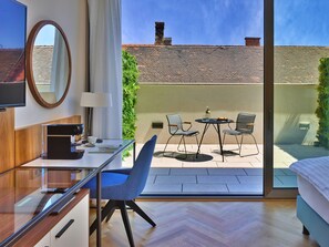 A modern hotel room with a large sliding glass door to an outdoor patio, a desk with a coffee machine, two chairs, and a bed. - EST Grand Hotel Savoy (Budapest)