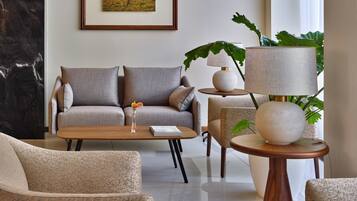 A modern living room with a sofa, armchairs, a coffee table, and a lamp.