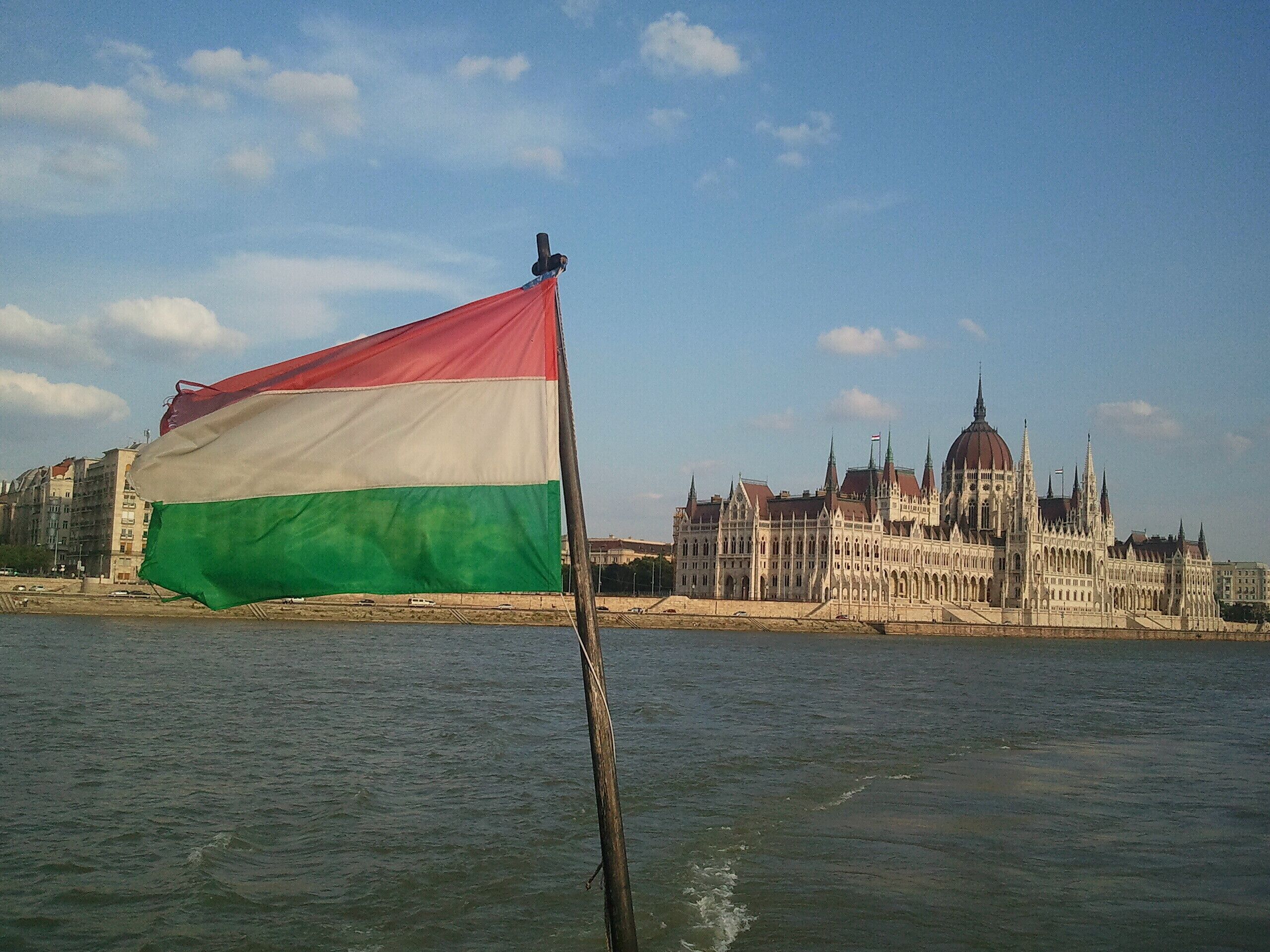Un asta con una bandera frente a un edificio histórico junto al agua.