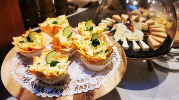 A variety of appetizers on a wooden board with a lace doily, including some with cucumber and cheese.