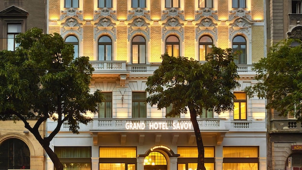 Un hotel imponente con detalles arquitectónicos ornamentales, ventanas amplias y una entrada destacada.