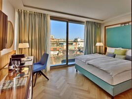 A hotel room with a large bed, a desk with a coffee machine, and a chair.