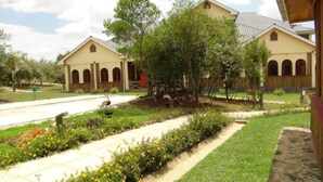 A residential area with two beige houses, each with a distinct arched window design. - The Nelion (Naro Moru)
