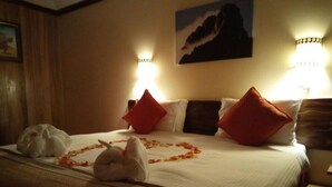 A hotel room with a neatly made bed, red pillows, and a bouquet of flowers on the bed. - The Nelion (Naro Moru)