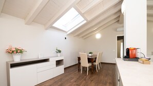 Une cuisine moderne dotée d’une verrière, d’un plancher en bois, d’un coin repas avec des chaises et d’une machine à café.
