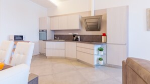 Una cocina moderna con armarios blancos, horno empotrado y cafetera.