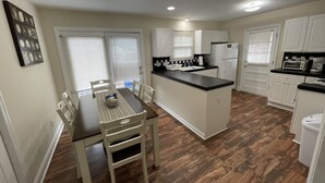 A modern kitchen with a dining area, white cabinetry, a central island, and a black countertop.
