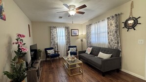 A living room with a ceiling fan, two sofas, a coffee table, and a TV.