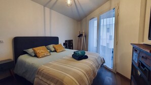 A bedroom with a bed, pillows, a bedside table, a lamp, and a view of the outside through a window. - Le petit marquisat à deux pas du lac (Annecy)