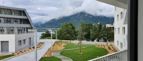 A modern building with a balcony overlooking a landscaped garden and a mountainous landscape.
