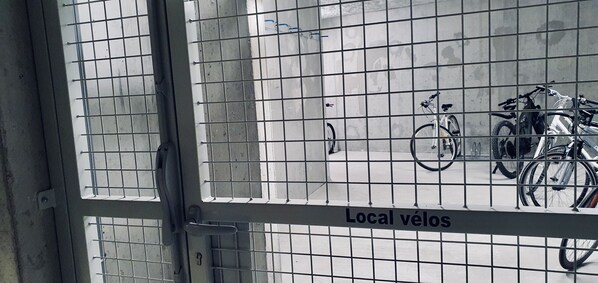 A metal gate with a sign reading "Local vélos" and bicycles parked behind it.