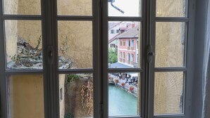 A view through a window with a stone wall and a narrow waterway. - Le Thiou / Old Town - Nearby Lake (Annecy)