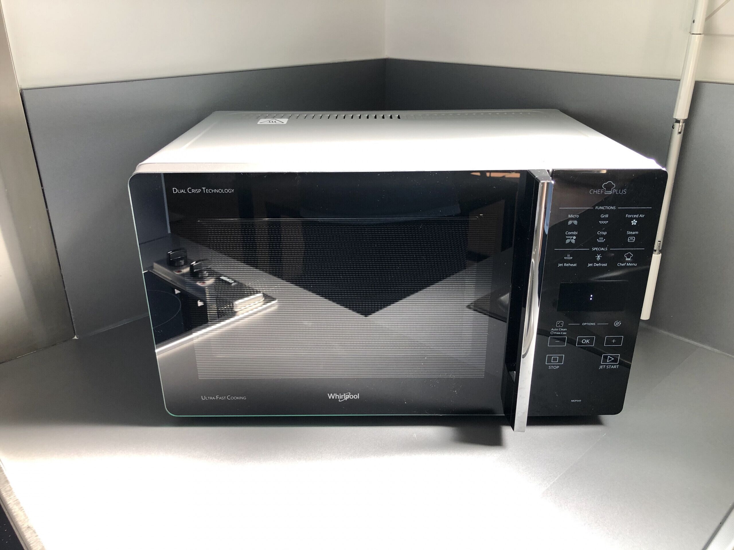 Un horno microondas Whirlpool con pantalla digital, panel de control e interior negro.
