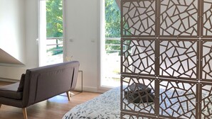 A modern bedroom with a bed, a bench, and a view of greenery outside. - The Lodge 106 apartment at the foot of Semnoz (Sévrier)
