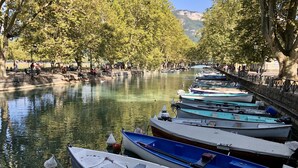 A row of boats docked along a riverbank with trees and a distant mountain view. - The Lodge 106 apartment at the foot of Semnoz (Sévrier)