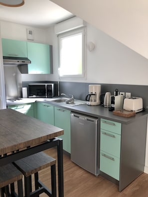 A compact kitchen with a microwave, coffee maker, toaster, and dishwasher.