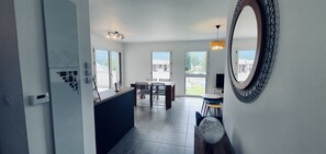 A modern kitchen with a central island, large windows, and a dining area with a view.