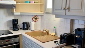 A kitchen with a stove, oven, coffee maker, toaster, and a sink. - Studio en bordure de Lac (Doussard)