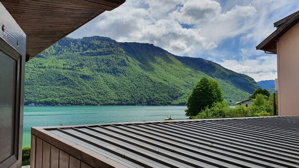 A view from a balcony overlooking a lake with mountains in the background. - Studio en bordure de Lac (Doussard)