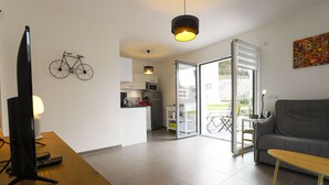Un soggiorno moderno con una TV a schermo piatto, un tavolino di legno, un divano e un'area pranzo con tavolo e sedie.