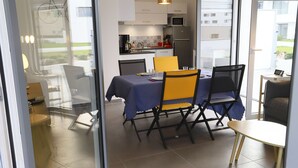 Zona pranzo moderna con tavolo apparecchiato per due, cucina sullo sfondo e vista esterna.