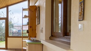 Un couloir avec un plafond en bois, une fenêtre donnant sur l’extérieur, une petite armoire en bois et une porte menant à une autre pièce.