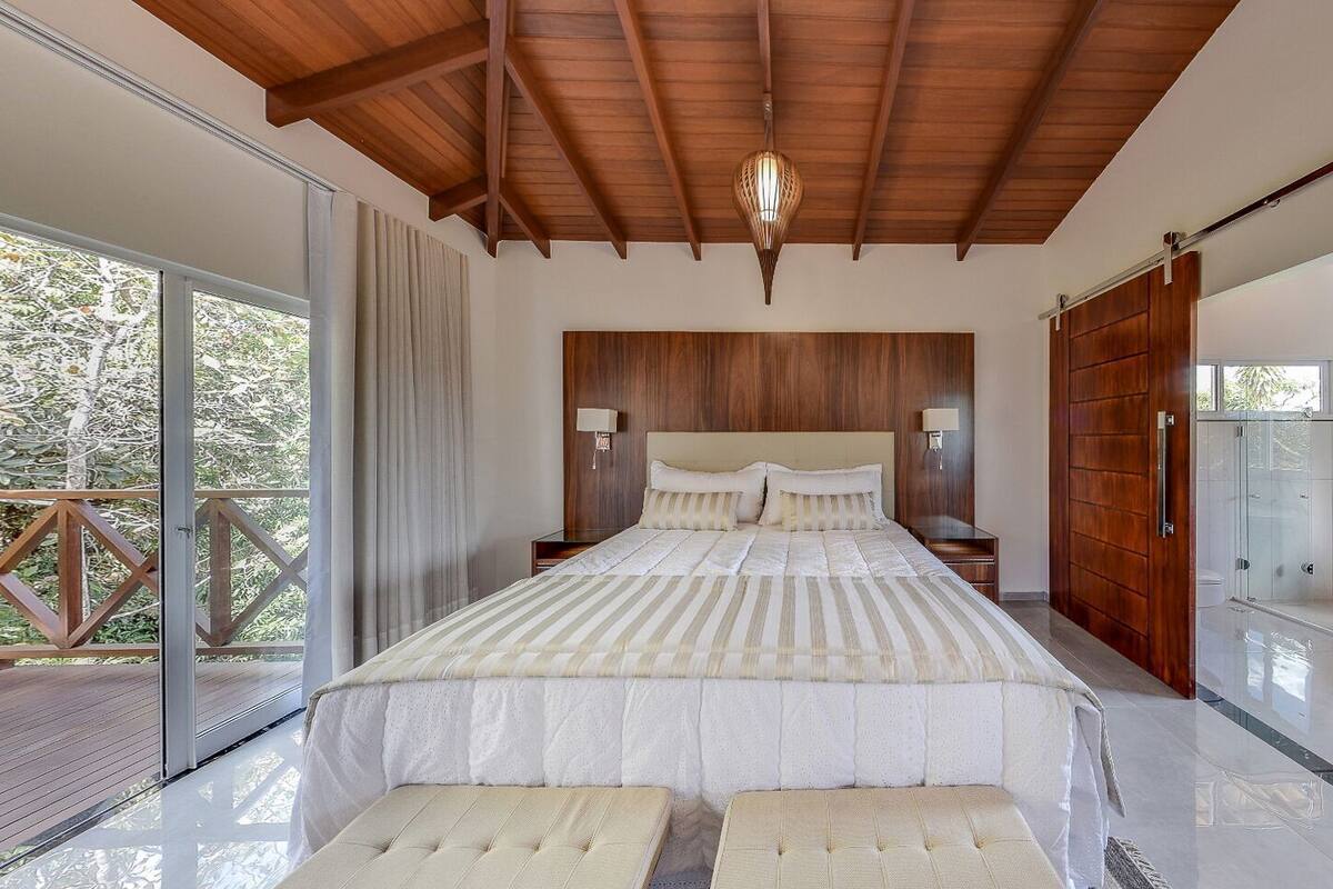 Une chambre avec un grand lit, un plafond en bois et une douche en verre.