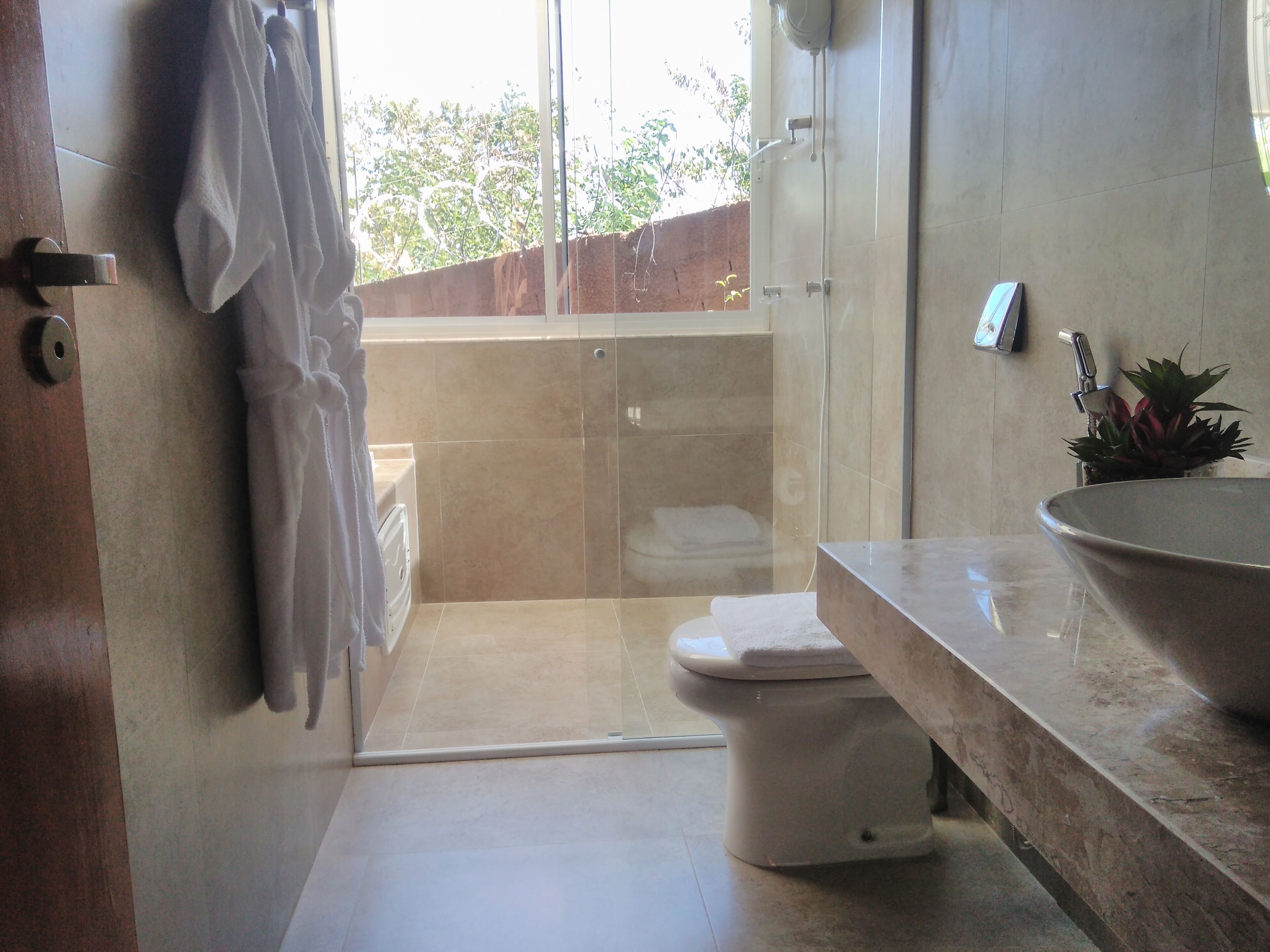 A modern bathroom with a glass shower enclosure, a toilet, a sink with a large bowl, and a towel rack.