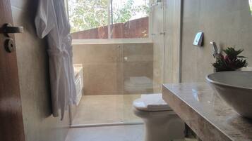 A modern bathroom with a glass shower enclosure, a toilet, a sink with a large bowl, and a towel rack.