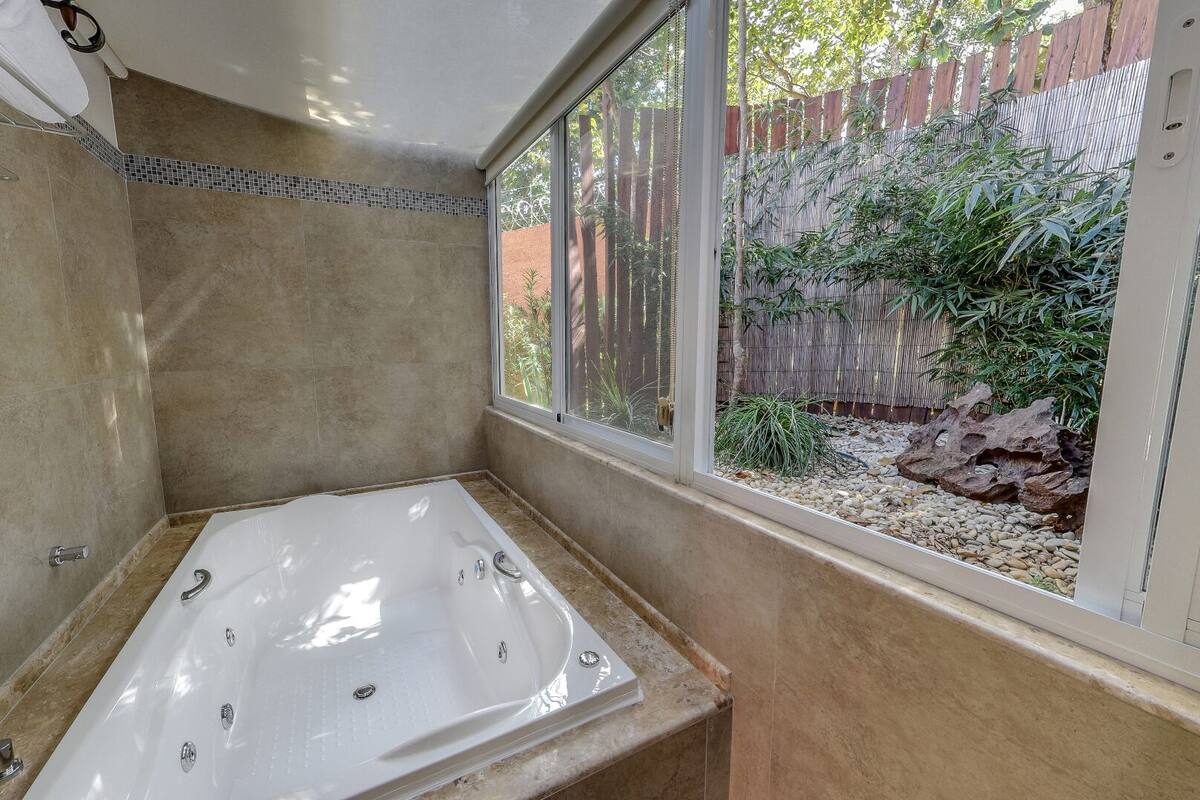 Une salle de bain avec une baignoire, une fenêtre et une vue sur un jardin.