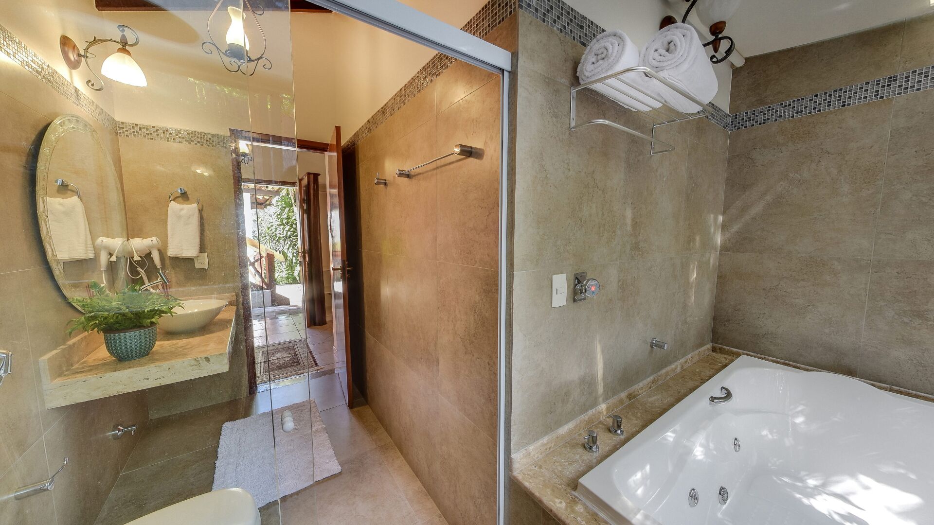 Une salle de bain moderne dotée d’une grande baignoire, d’une douche à parois de verre et d’un meuble-lavabo avec un miroir et un porte-serviettes.