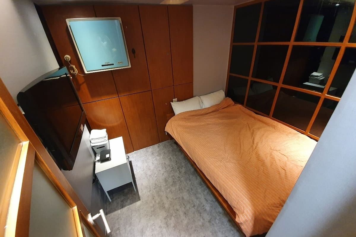 Un dormitorio pequeño con cama, escritorio y armario.