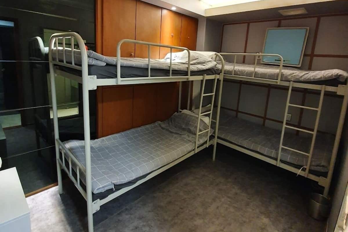 Habitación con literas, un armario de madera y un escritorio pequeño.