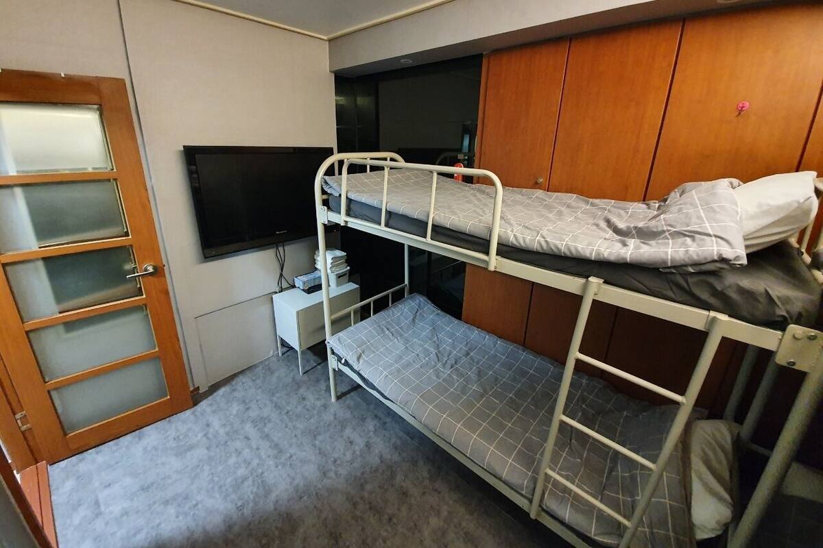 Habitación con literas, televisor, un escritorio pequeño y un armario.