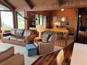 L’intérieur chaleureux d’un chalet avec des canapés en cuir, une table à manger et un coin cuisine.