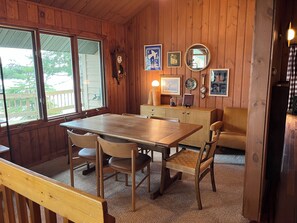 L’intérieur d’un chalet en bois comprend une table à manger, des chaises, un canapé et une grande fenêtre.