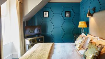 Ein modernes Schlafzimmer mit einer Türkis-farbenen Akzentwand, einem Bett mit gemusterten Kissen, einer Kommode und einem Fernseher.