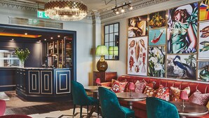 Een bar met een toonbank, barkrukken en een zithoek met een bank en stoelen.