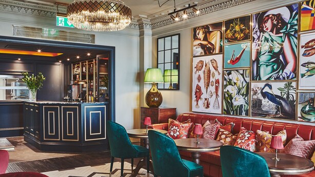 Zona de bar con barra, taburetes y un espacio de estar con sofá y sillones.
