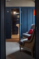 A room with a vintage armchair, a blue door leading to a bathroom, and a patterned floor.
