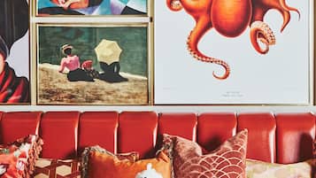 A red leather sofa with a table in front, holding plates of food, cups, and a teapot.