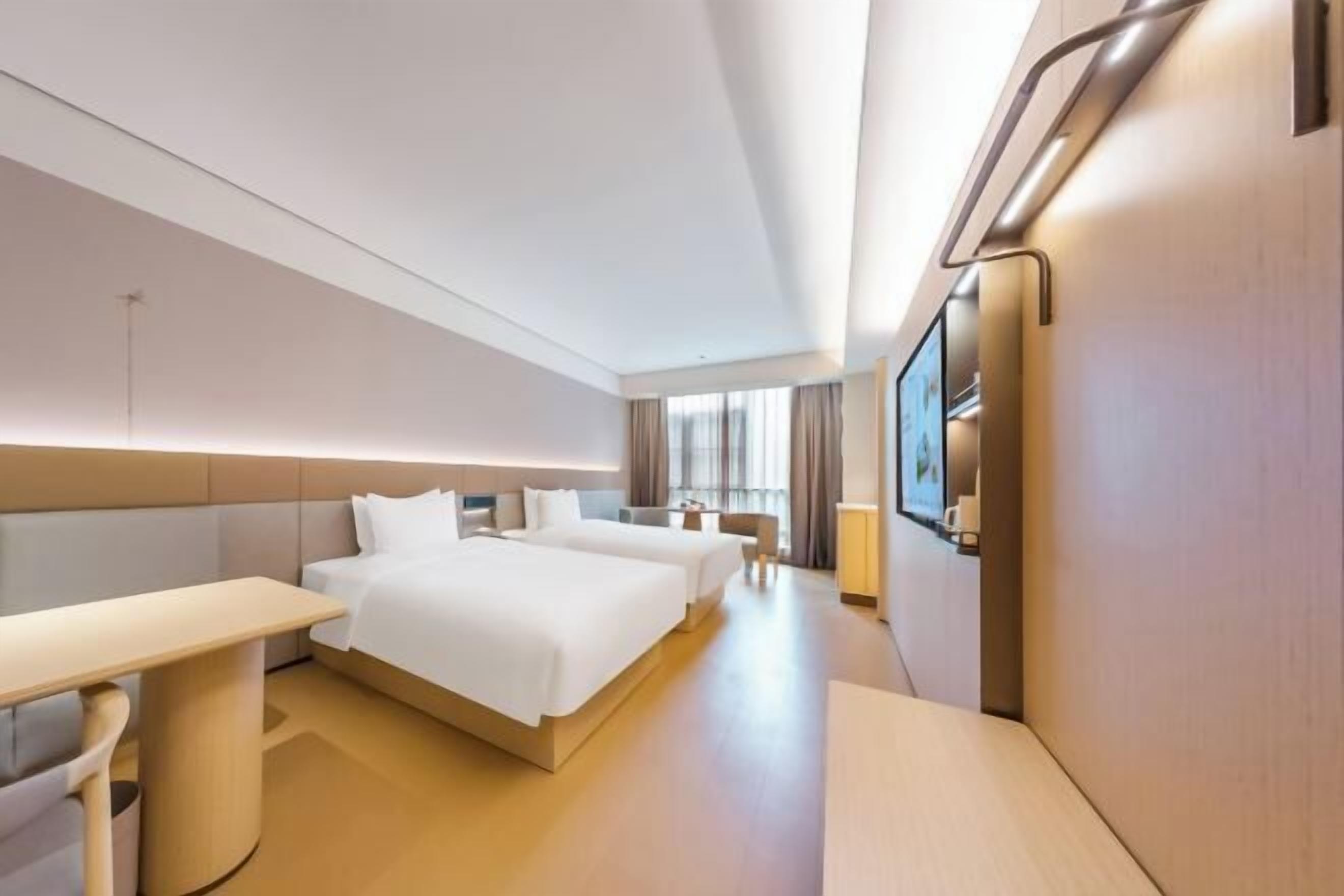 A modern hotel room with a large bed, a desk, and a TV.