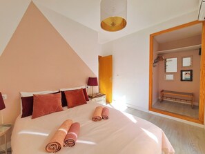 A bedroom with a large bed, a bedside table, a lamp, a mirror, and a bench. - APARTMENT WITH 2 TERRACES AND PARKING IN THE SAME BUILDING (Cartagena)