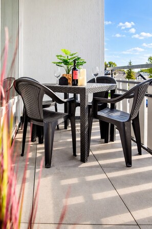 An outdoor patio with a table and chairs, a potted plant, candles, and a bottle of wine. - Smart Resorts - Maison Brilliant - Studio 610 with balcony, max. guests (Winterberg)