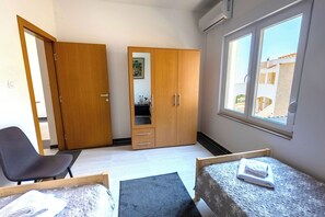 A bedroom with a bed, a chair, a wardrobe, and a window.