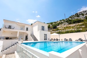 A two-story building with a swimming pool, outdoor seating, and a staircase leading to the upper level.