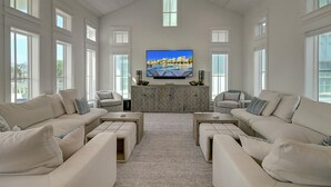 A spacious living room with a large flat-screen TV mounted on the wall, two sofas facing each other, and a patterned cabinet below. - Mod, Designer Beach Home w/ Great On-Site Amenities in Cinnamon Shore (Port Aransas)