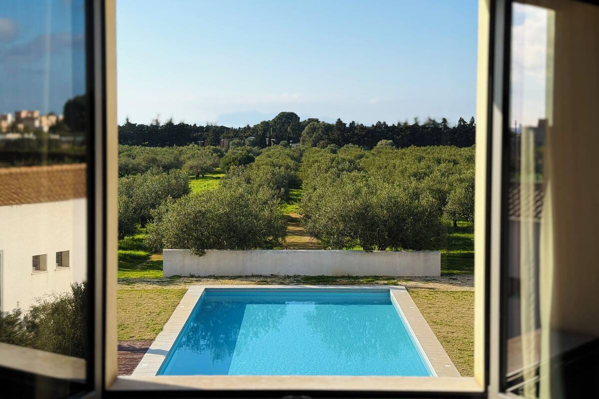 Piscina com vista para oliveiras e uma paisagem distante.