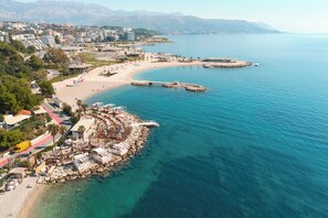 Ein Luftbild einer Küstenstadt mit Strand, felsiger Küstenlinie und Gebäuden entlang der Küste.
