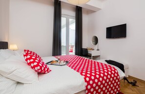 Ein Hotelzimmer mit Bett, Schreibtisch, Fernseher und einem Fenster mit Vorhängen.